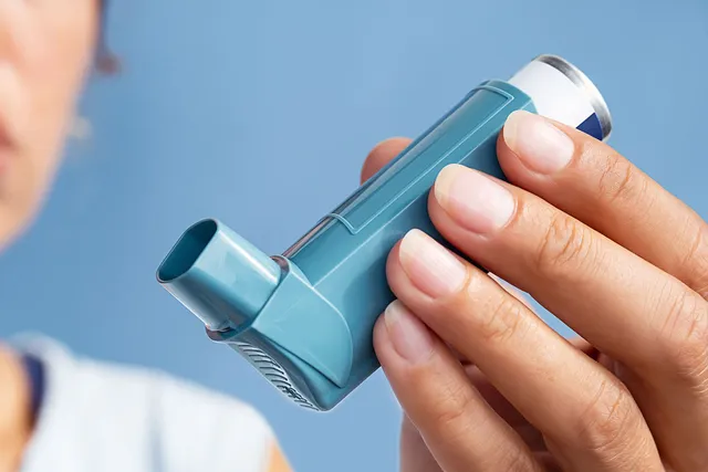 Hand hält ein Asthma-Inhalationsgerät